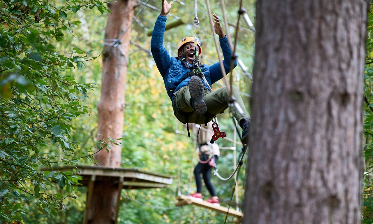 A man going down a zip wire on the Aerial Adventure.