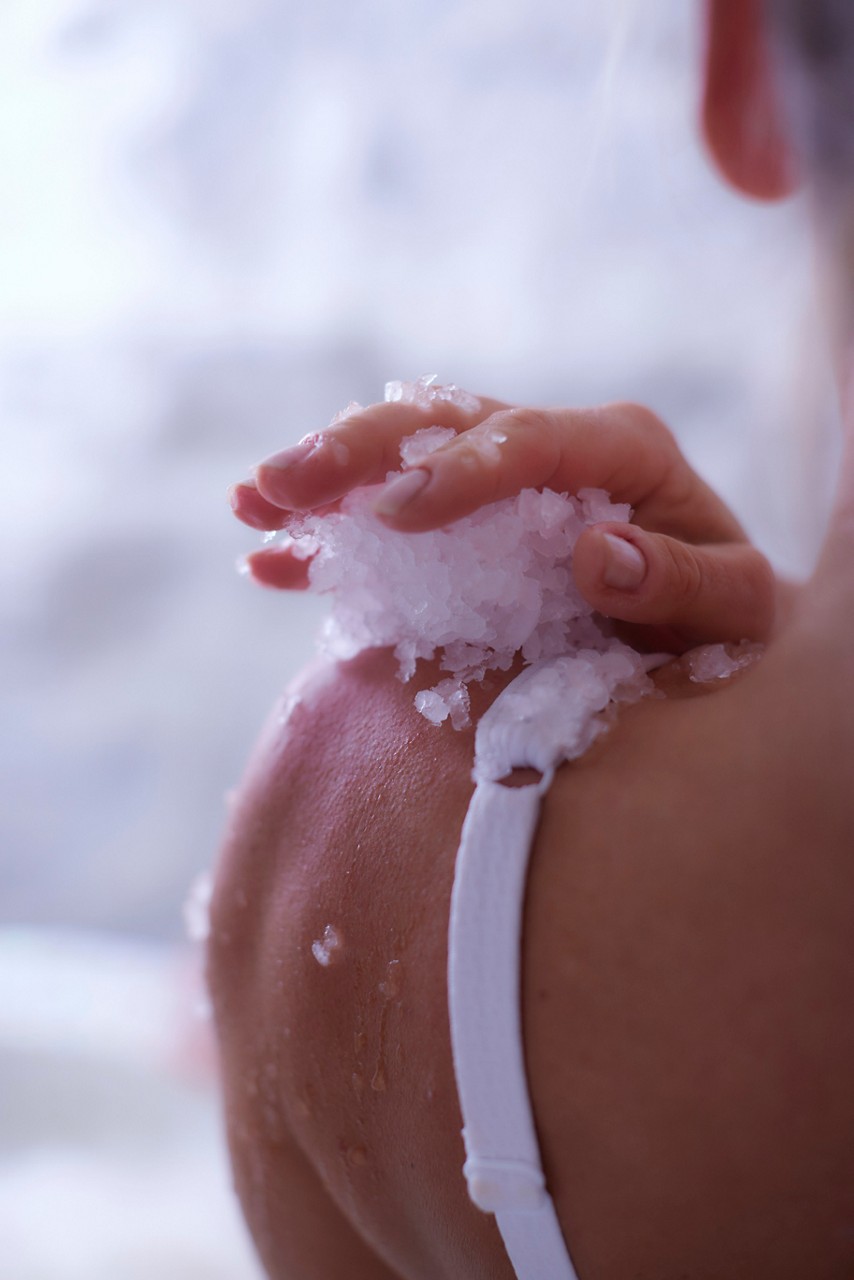 Woman stood in the Ice Cave applying shaved ice to her shoulder.