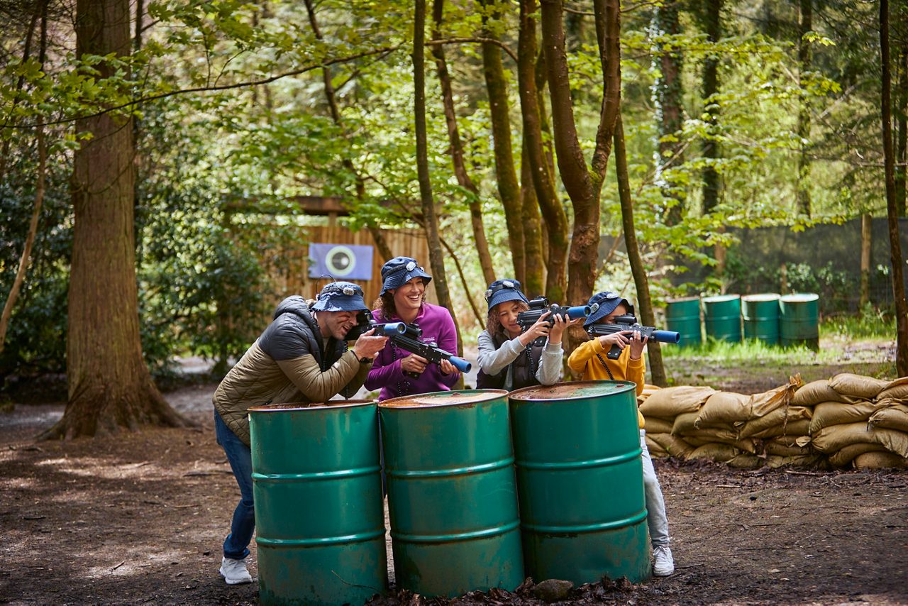 A family playing laser combat together in the forest.