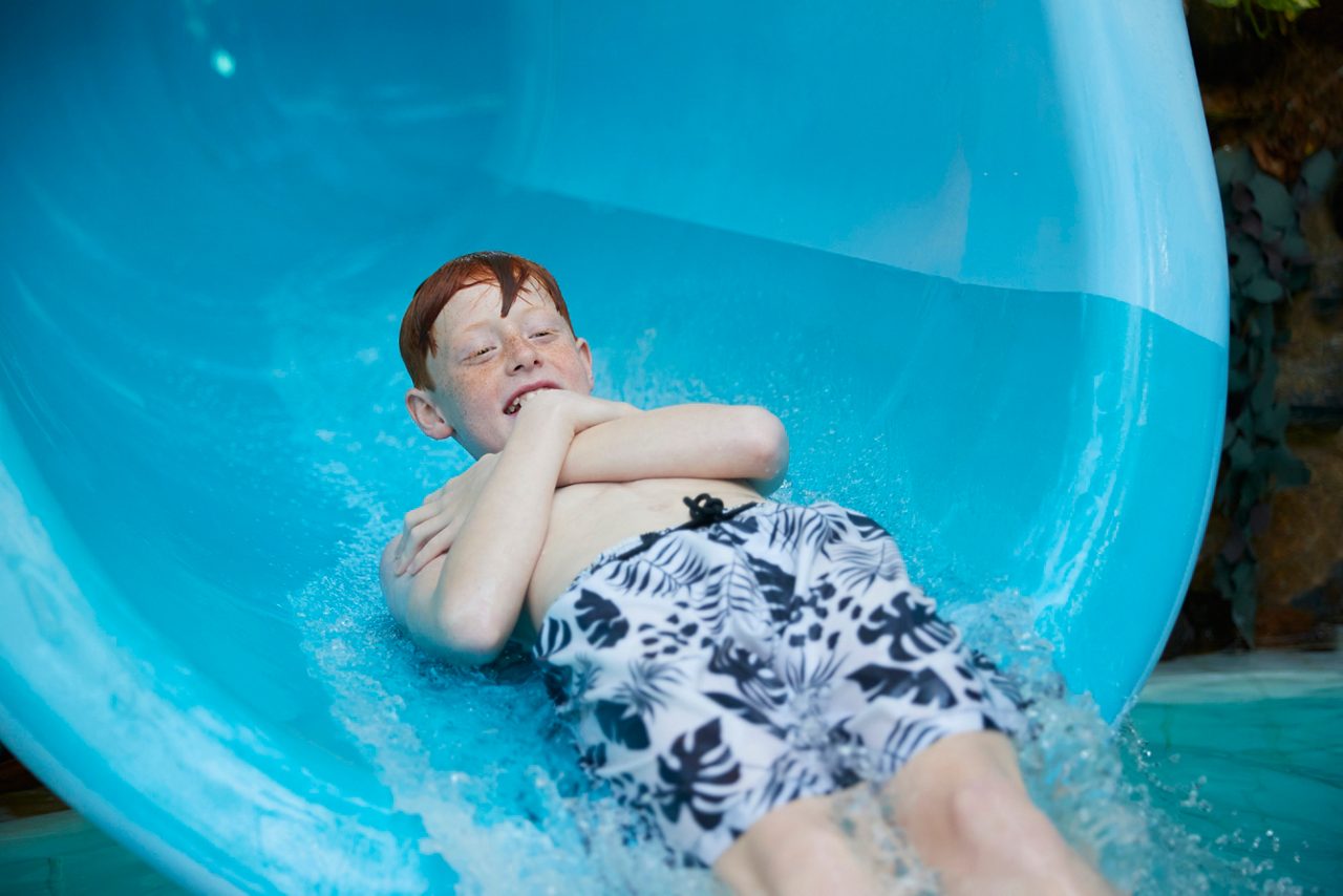 subtropical swimming paradise school age boy on slide