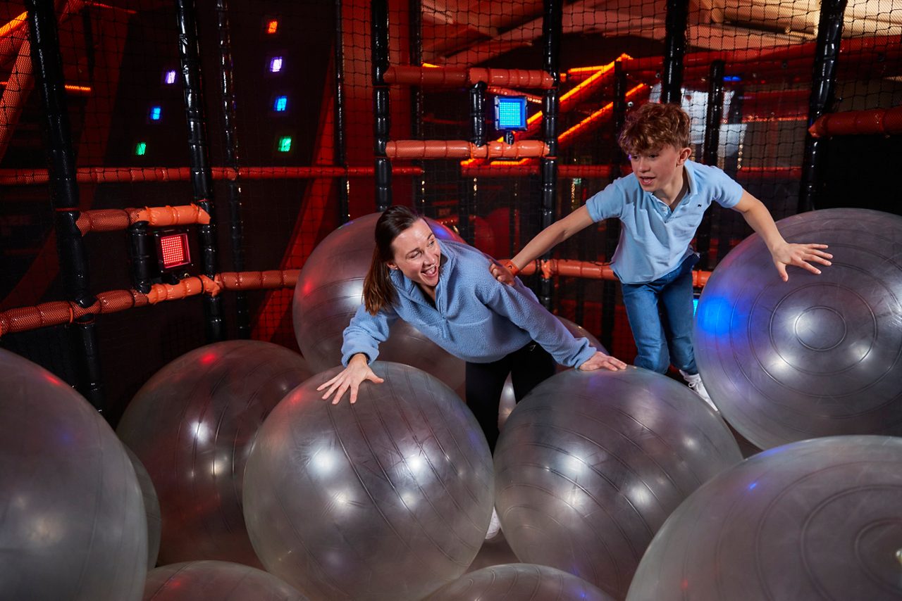 Two teens bouncing on the inflateable balls in the TAG challenge arena.