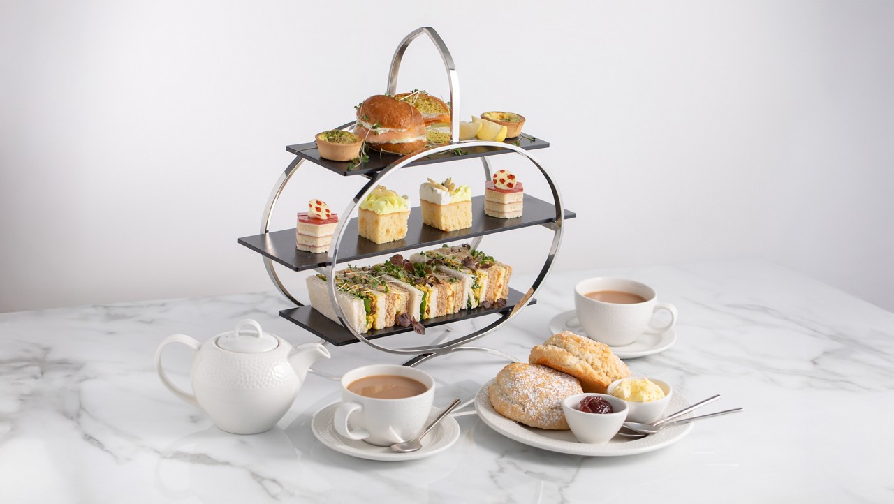 Afternoon Tea stacked with finger sandwiches, bite size cakes and scones, served with a pot of tea.