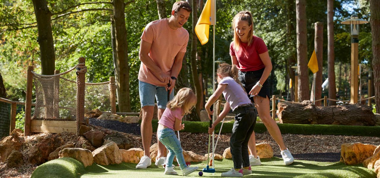 family outside in the sun playing adventure golf