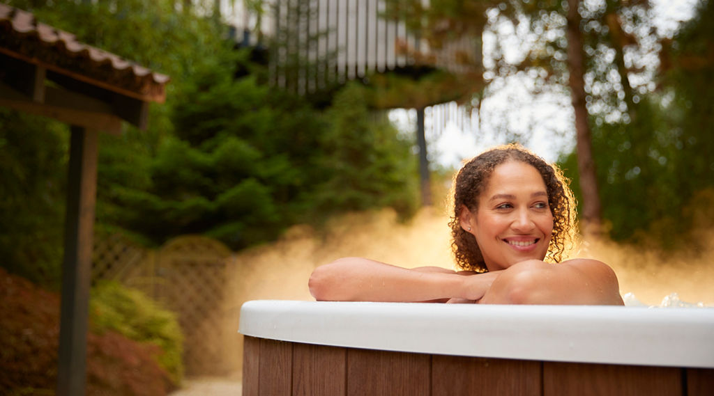Woman soaking in an outdoor pool surrounded by the forest.