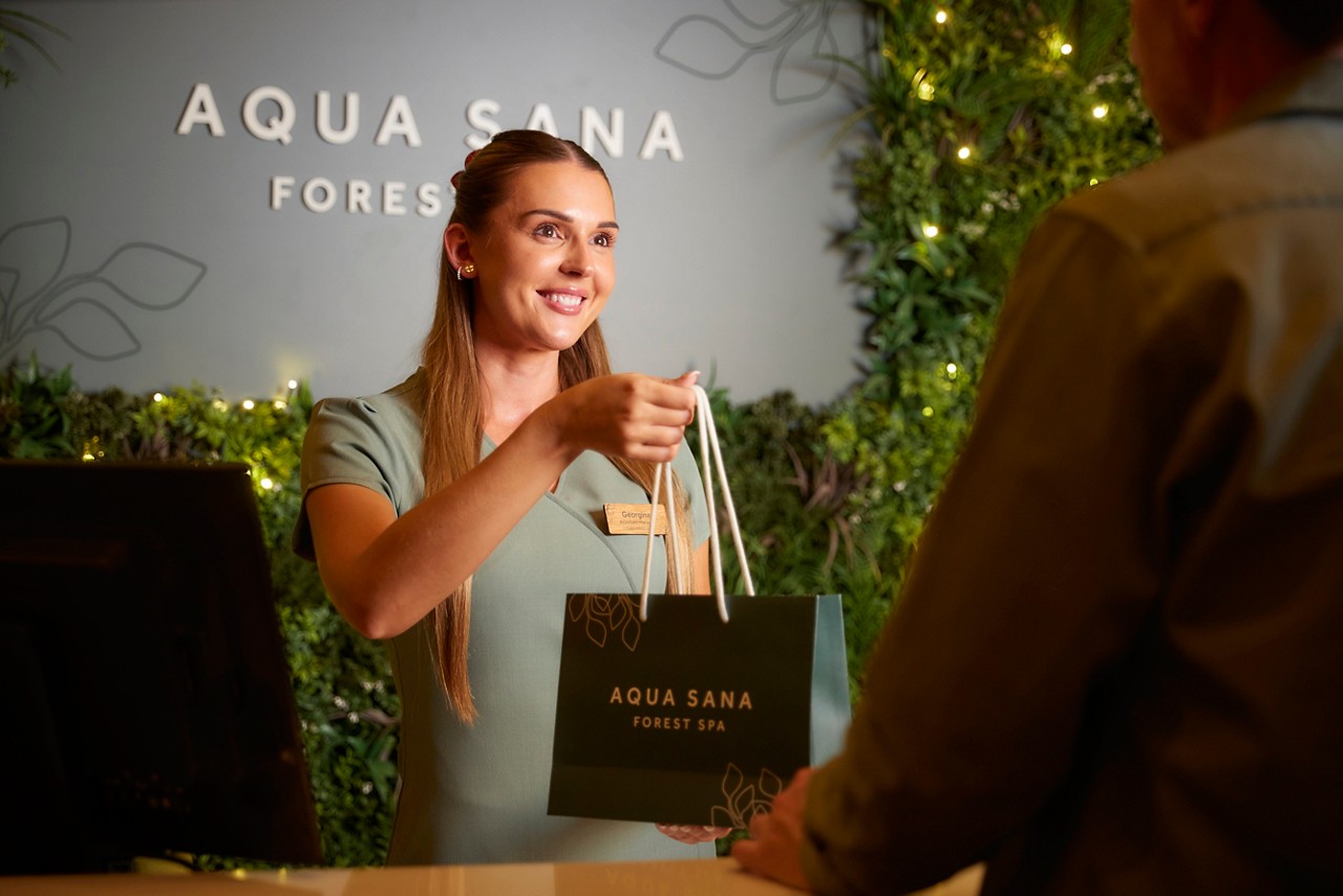 Spa therapist handing over a Aqua Sana Forest Spa branded bag.