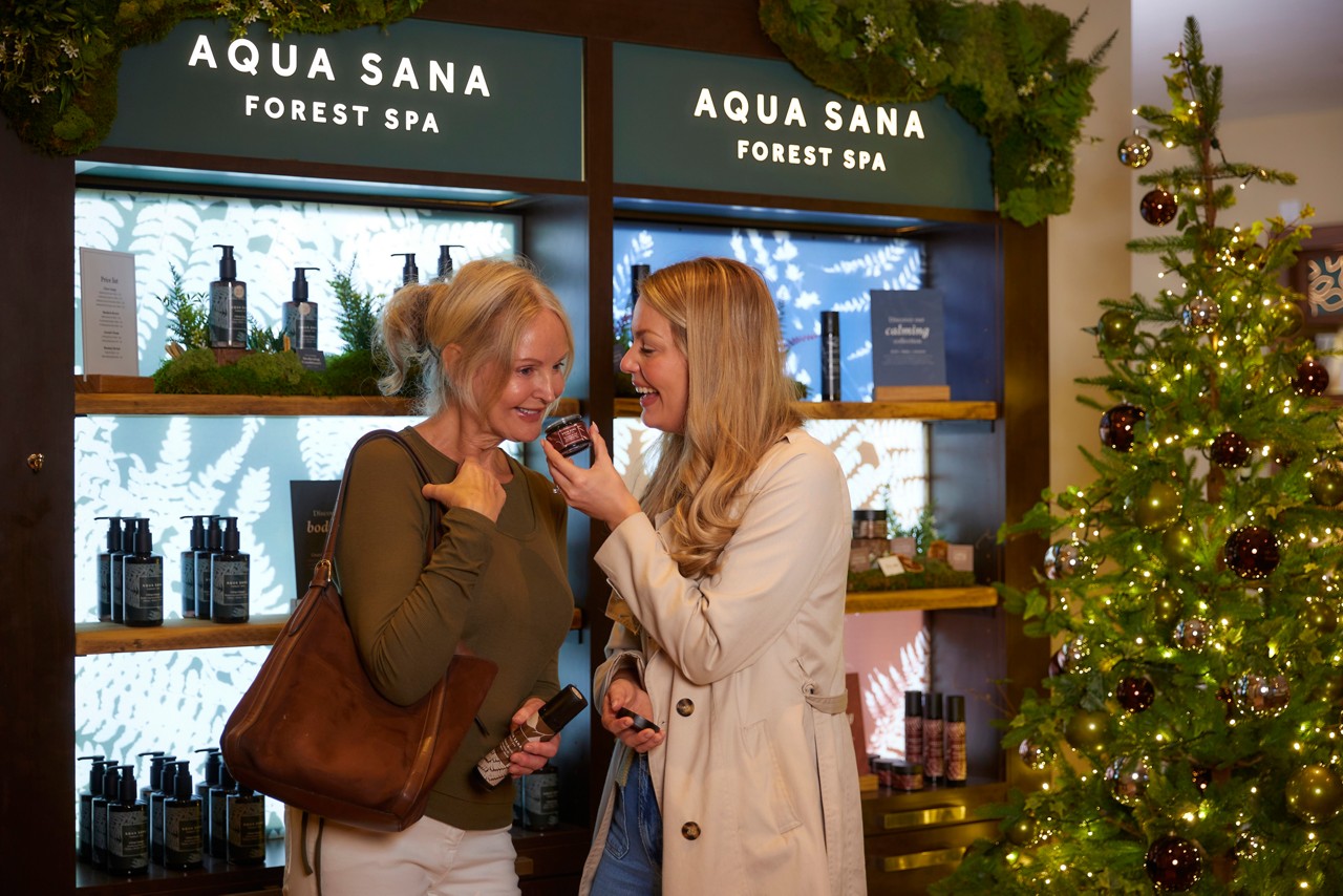 Two women smelling Aqua Sana Forest Spa products inside the Forest Spa Boutique.