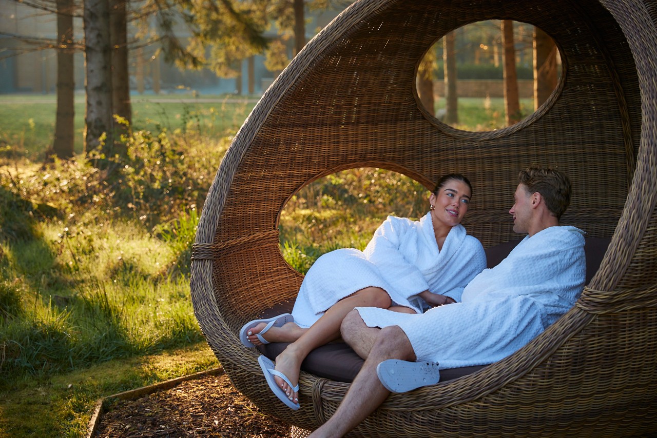 couple laid in lounge chair in forest awakening