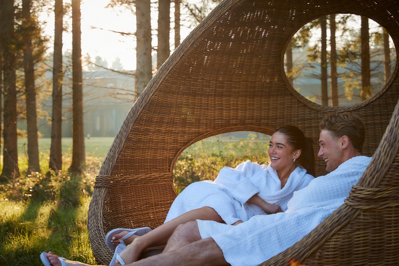 couple laid in lounge chair in forest awakening