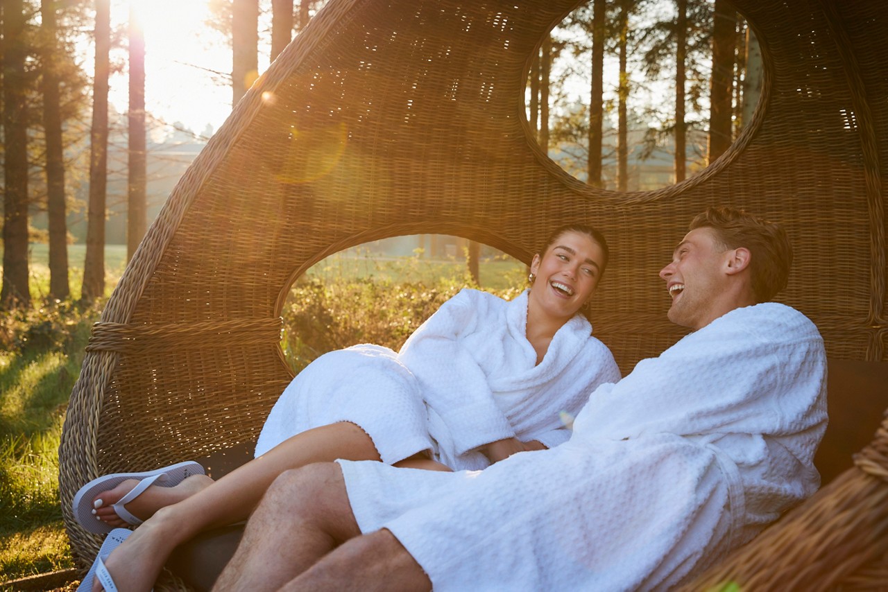 couple laid in lounge chair in forest awakening