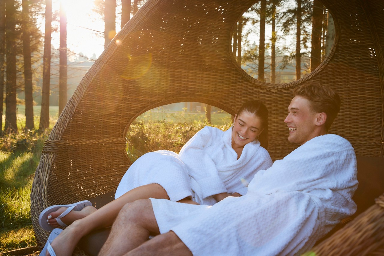 couple laid in lounge chair in forest awakening