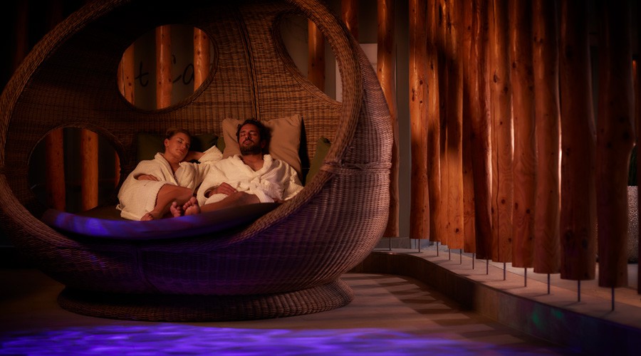 Couple snuggled in a large, cosy cocoon chair in the Forest Nesting area.