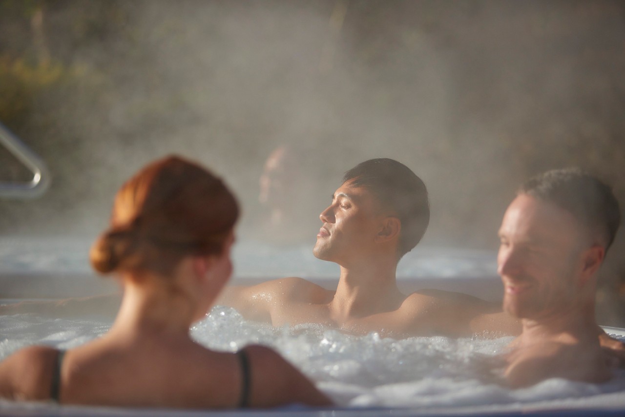 three people in an outdoor hot tub with steam surrounding them