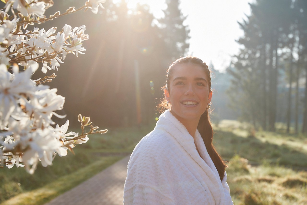 Woman smiling as she looks out at the forest.