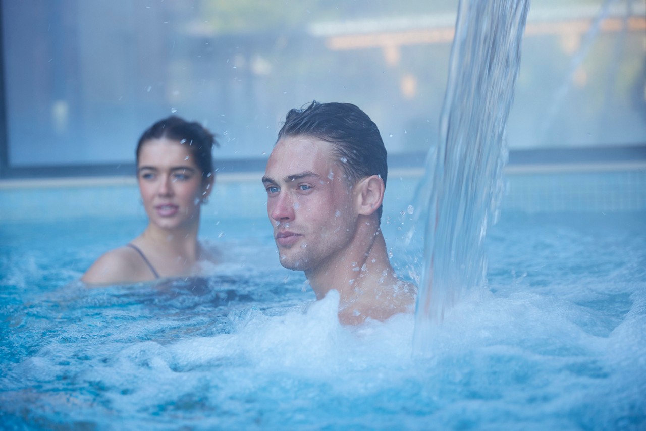 man under the water jet in the pool