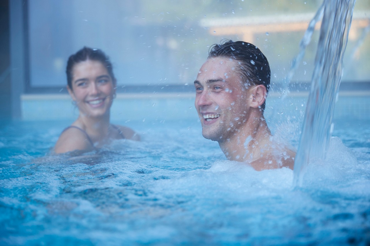 man under the water jet in the pool