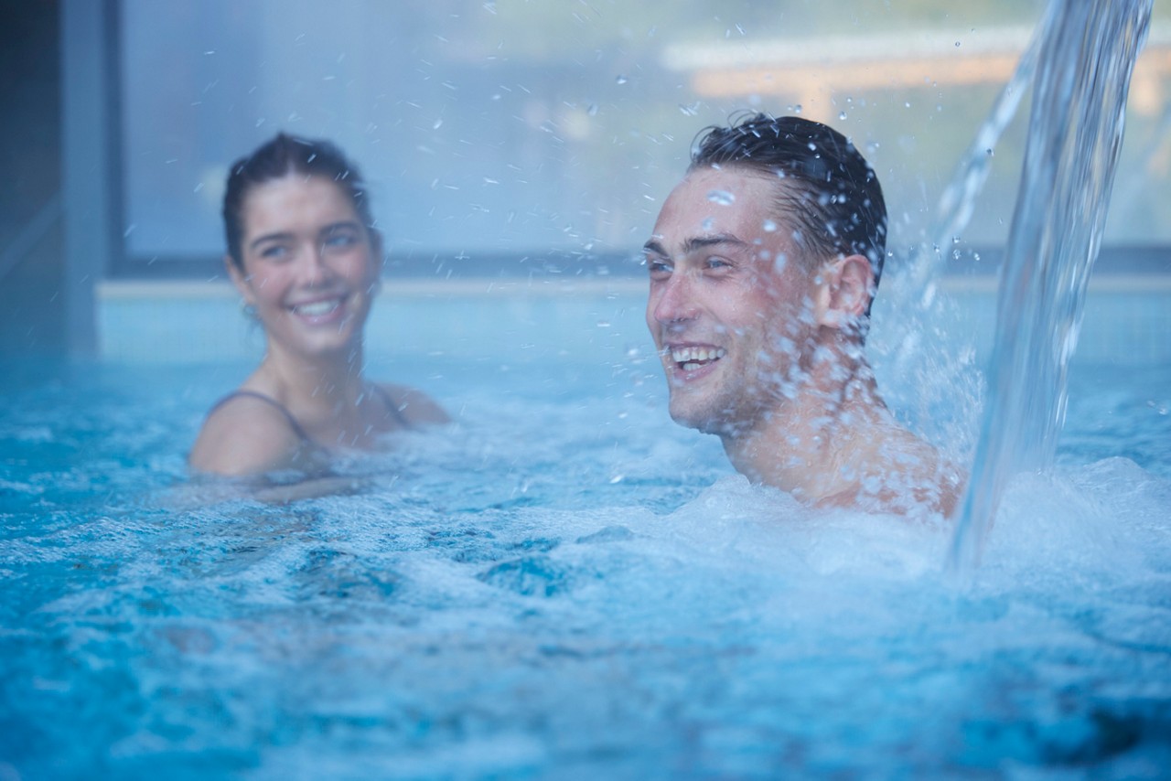 man under the water jet in the pool