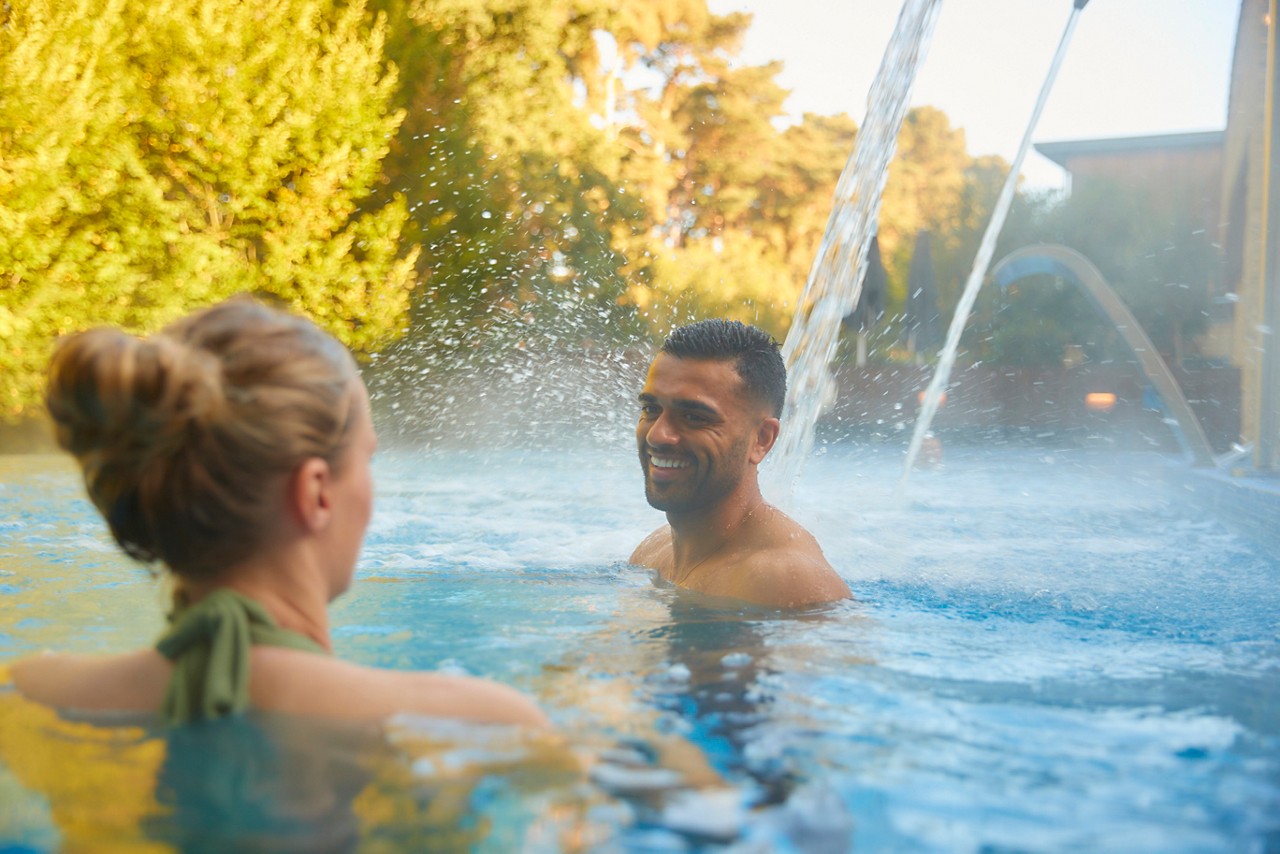 A man soaking in a steamy outdoor hot tub.