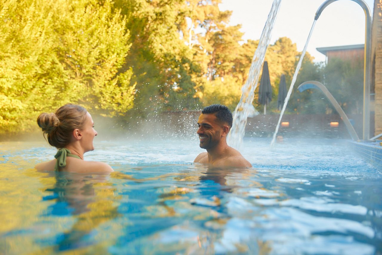two people in outdoor pool surrounded by forest