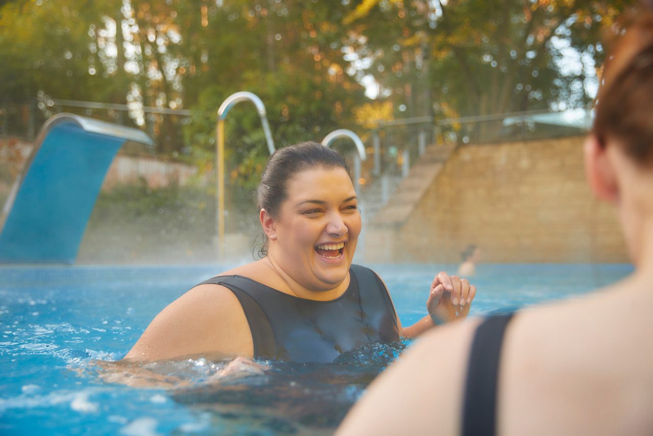 Woman soaking in an outdoor pool surrounded by the forest.