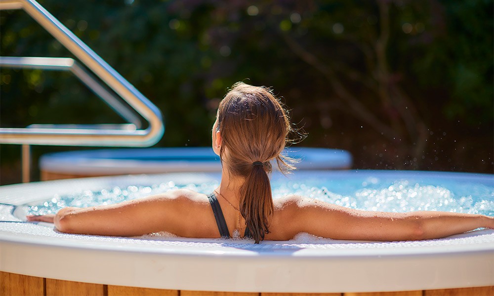 Woman soaking in a bubbling outdoor hot tub.