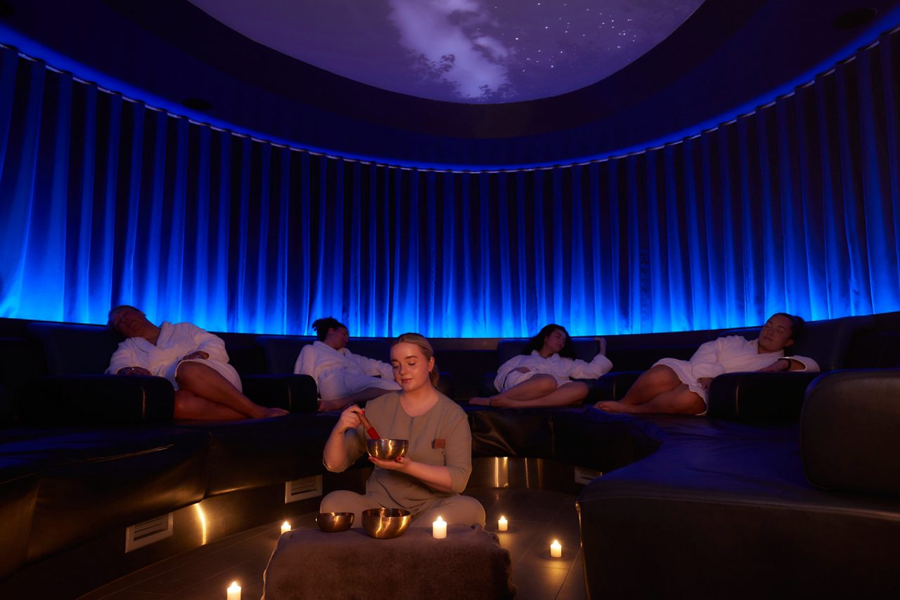 Spa therpaist leading a Sound Bathing Session with guests sleeping in a calming space.