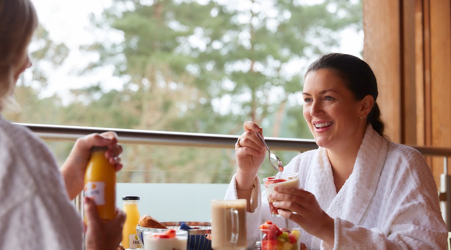 Two woman sitting having breakfast on their Spa Suite balcony.