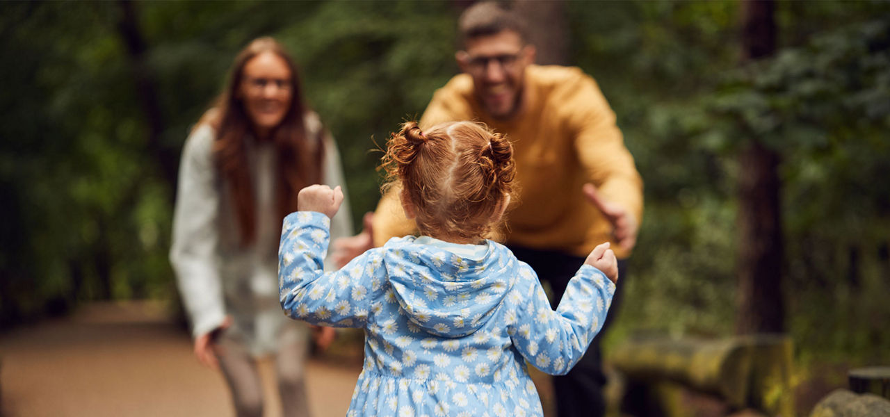 A young girl running to her parents in the forest