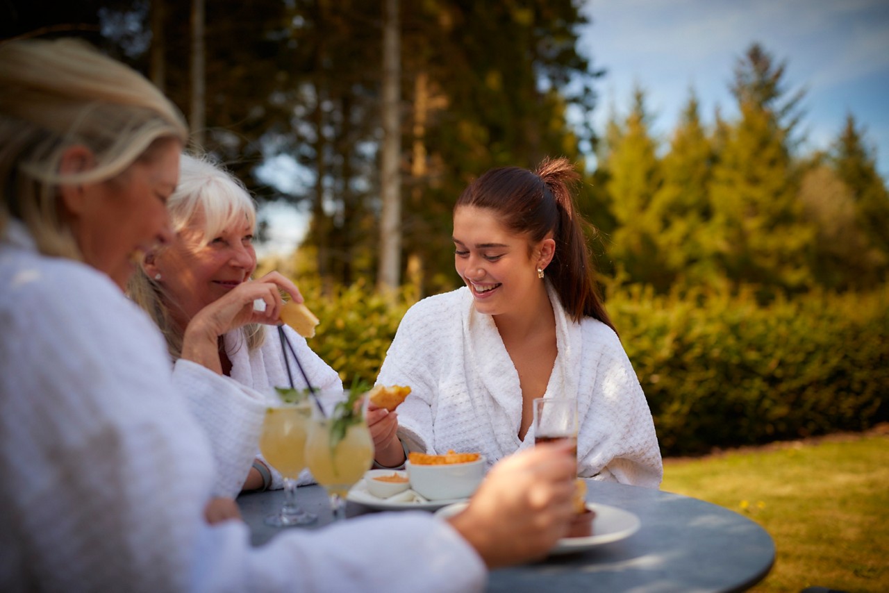 Women sitting enjoying drinks, surrounded by the forest.