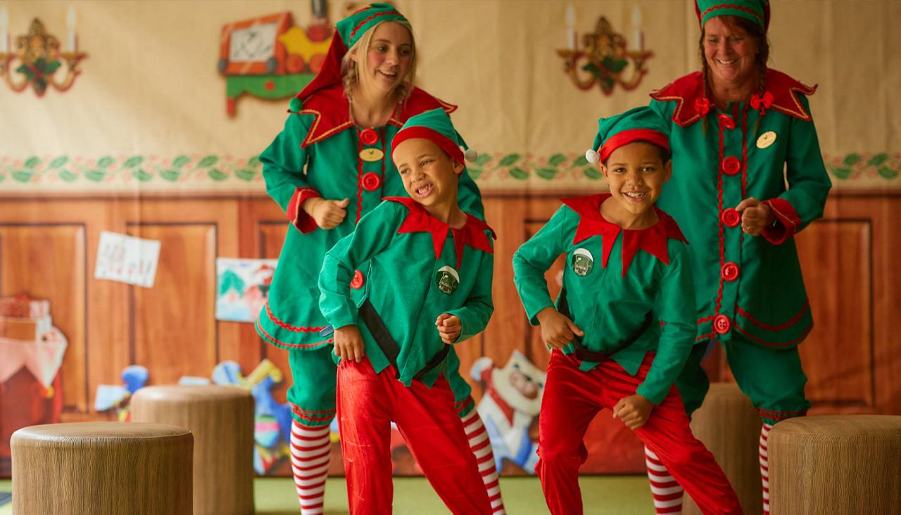 Two little boys dressed in elf costumes dancing with two elves